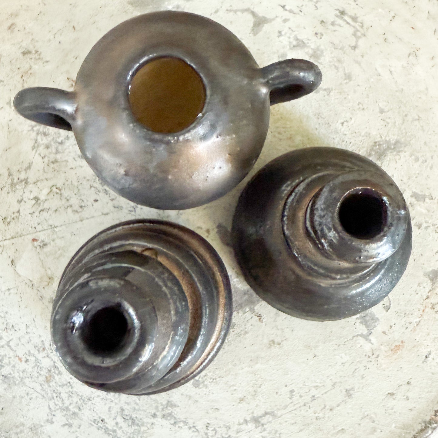 Three metallic objects with cylindrical shapes on a textured surface