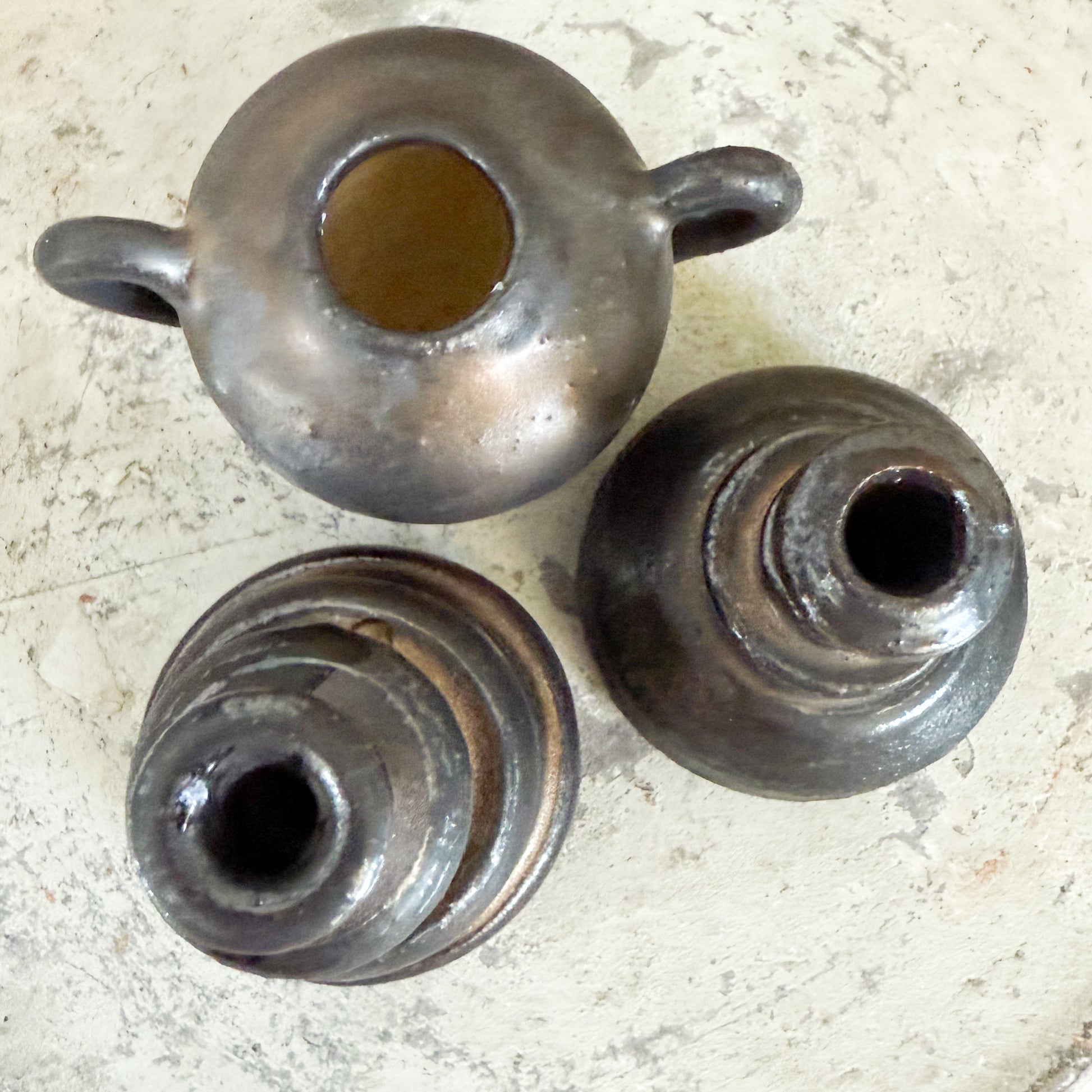 Three metallic objects with cylindrical shapes on a textured surface